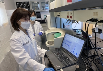 Jiyoung Lee, left, and PhD student Yuehan Ai check SARS-CoV-2 genetic copy data using droplet digital PCR.