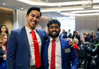 Two Master of Health Administration students in blue suits and red ties