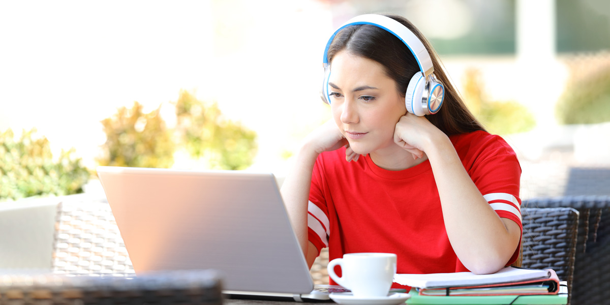 Woman with headphones studies on laptop