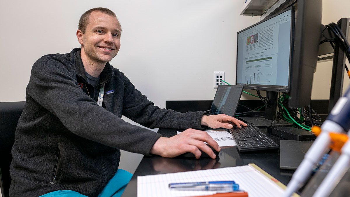 a student working at a computer smiles