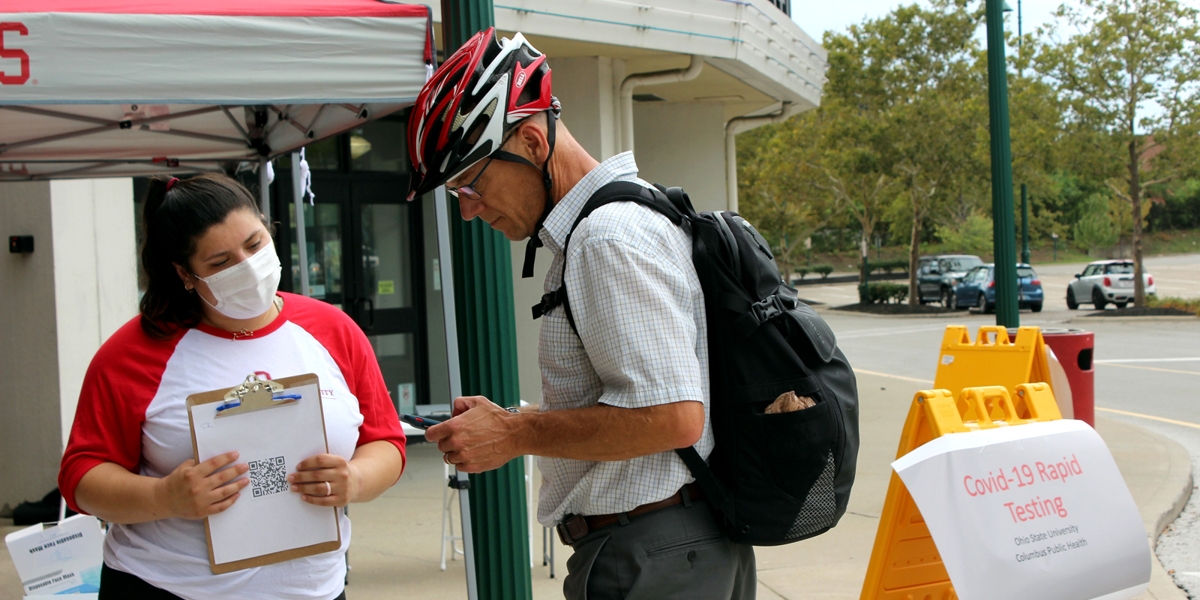 person holding clipboard helping community member sign up for medical appointment