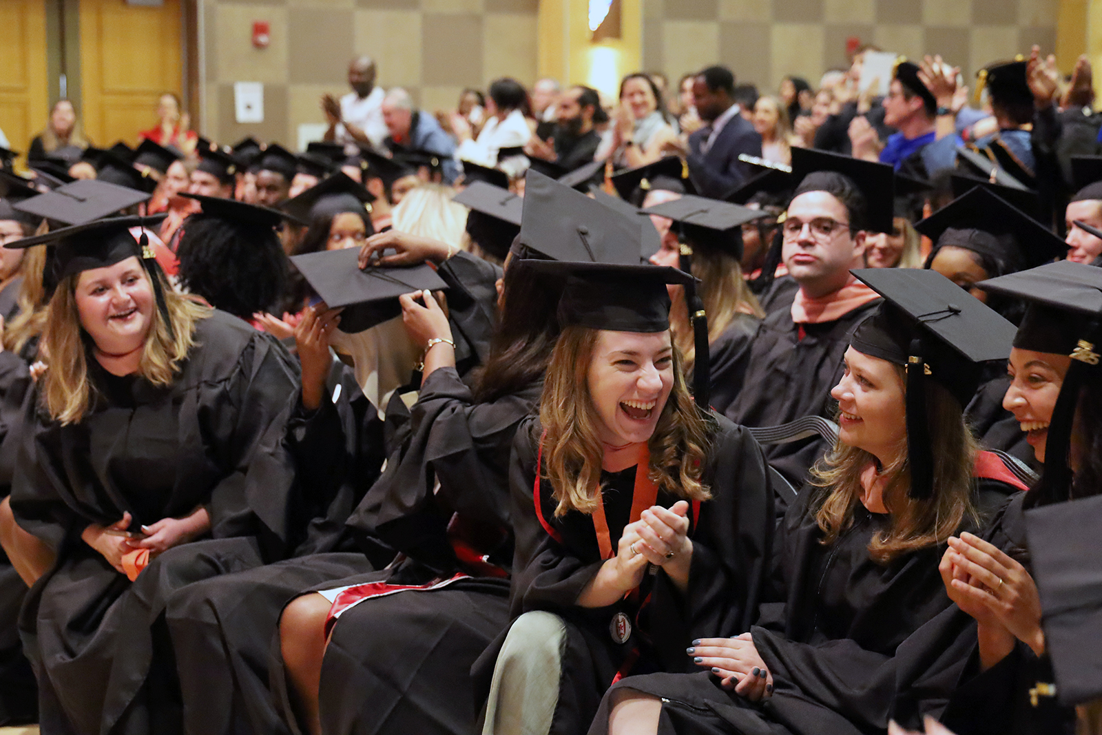 Students in regalia sitting and laughing