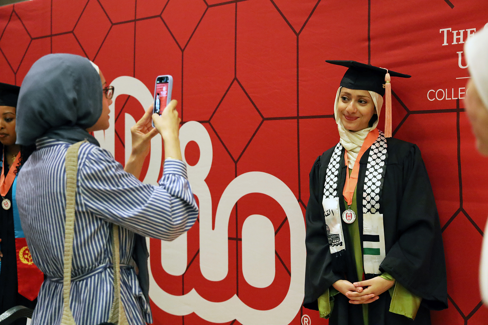 A student poses for a photo in front of a red backdrop