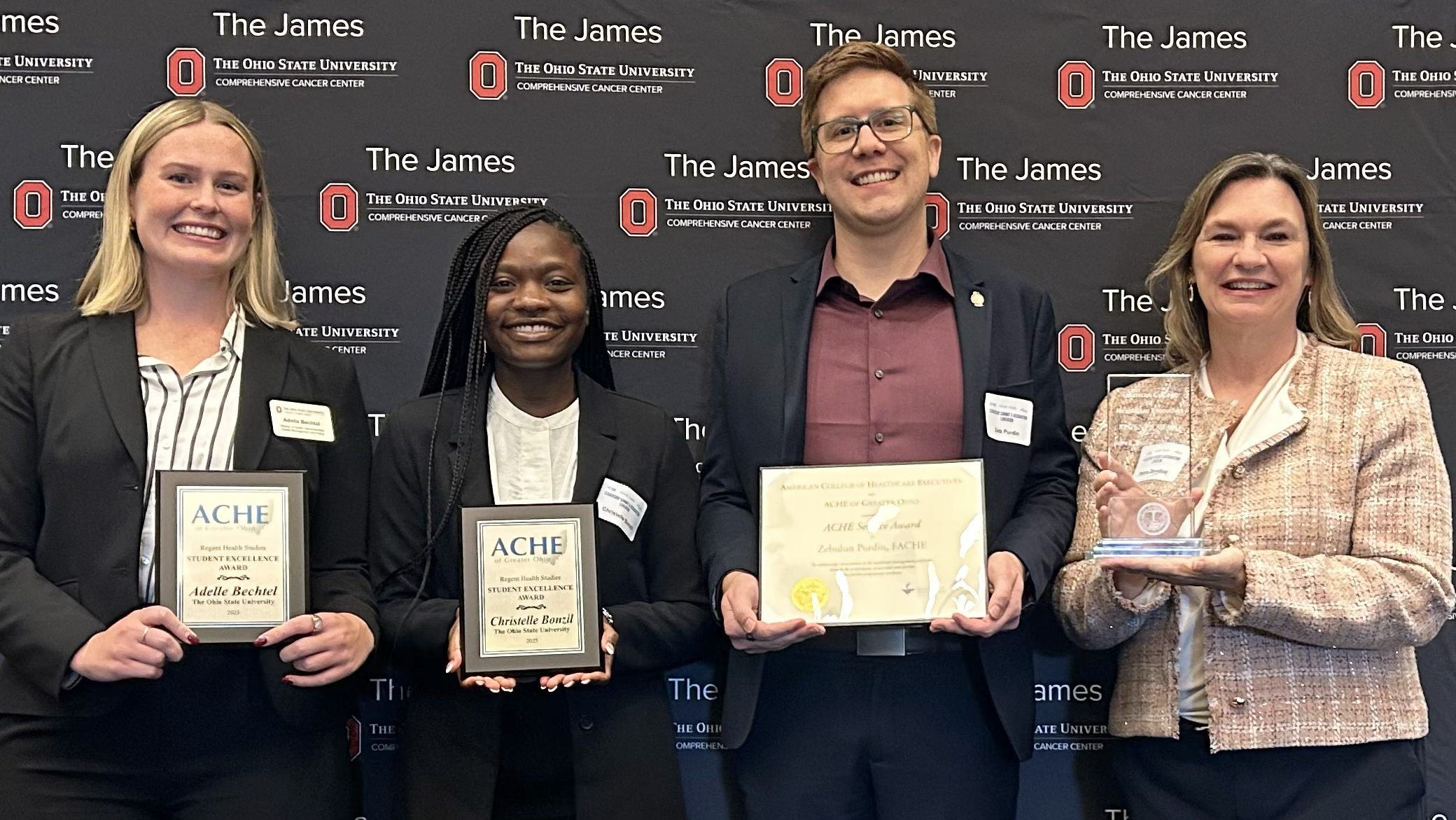 four people hold awards against a black blackfound