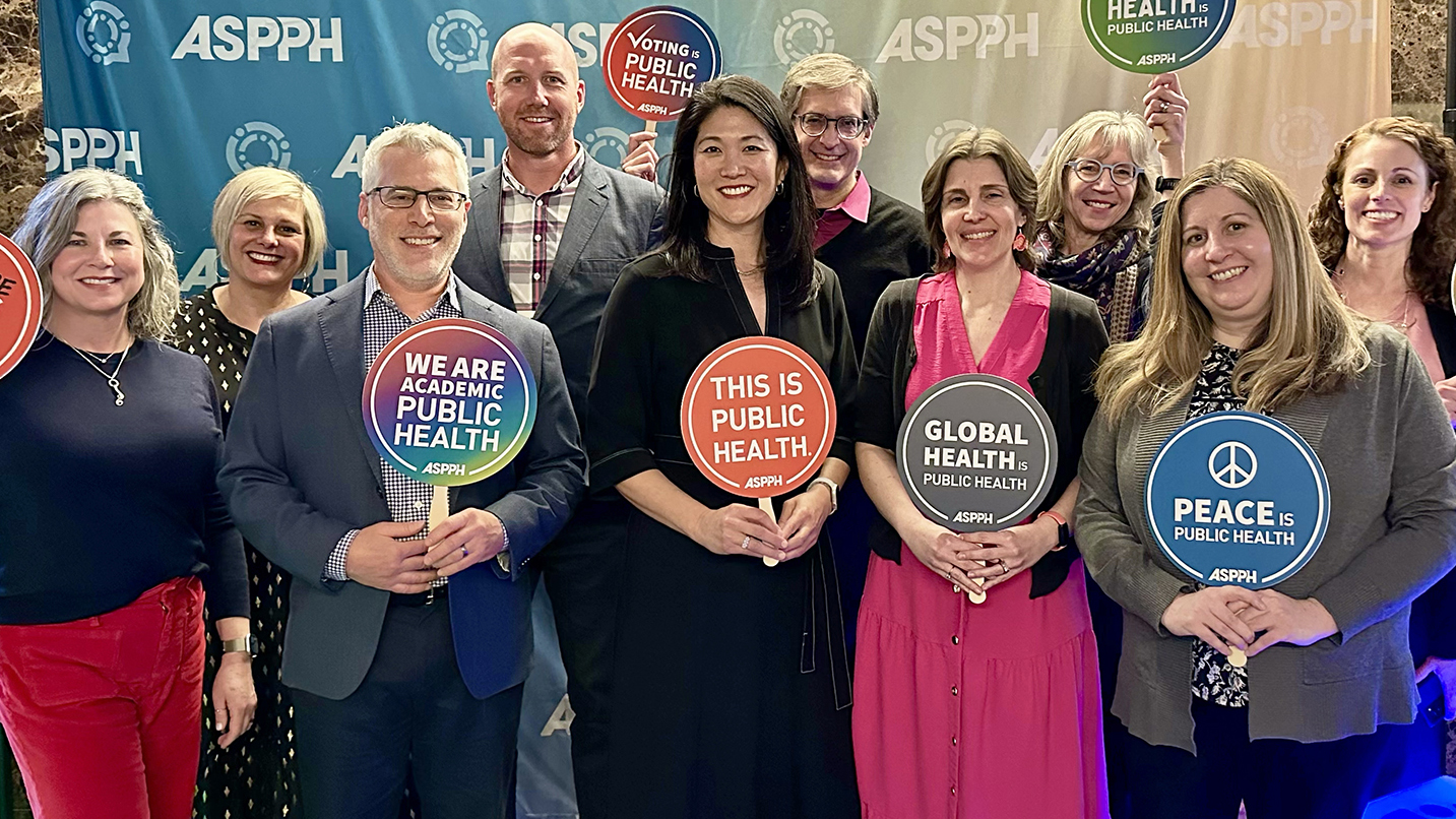 A group of people including Paula Song pose with signs supporting public health