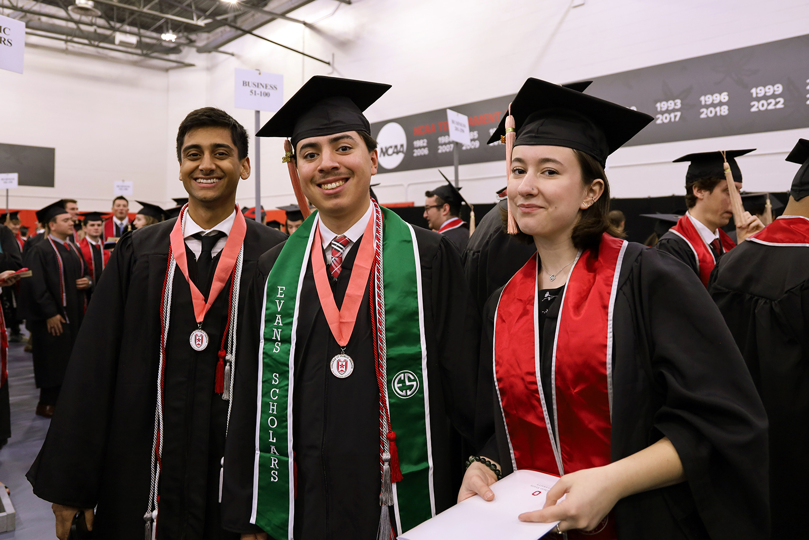 three graduates wearing regalia pose for a photo
