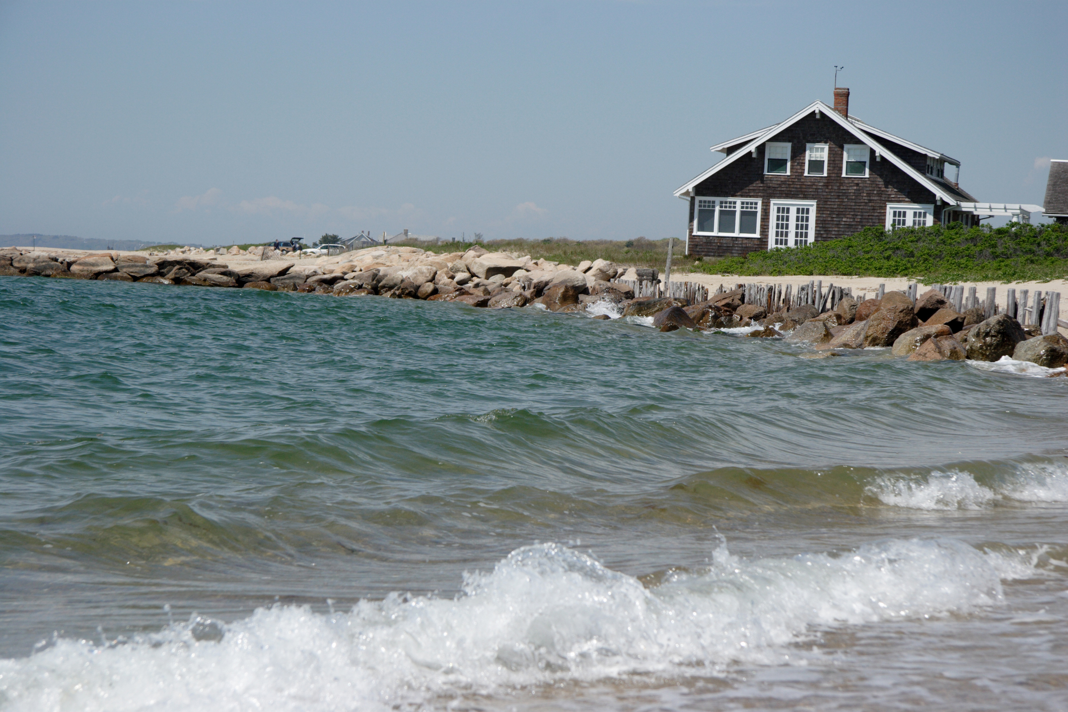 A small gray and white house on the edge of the seashore