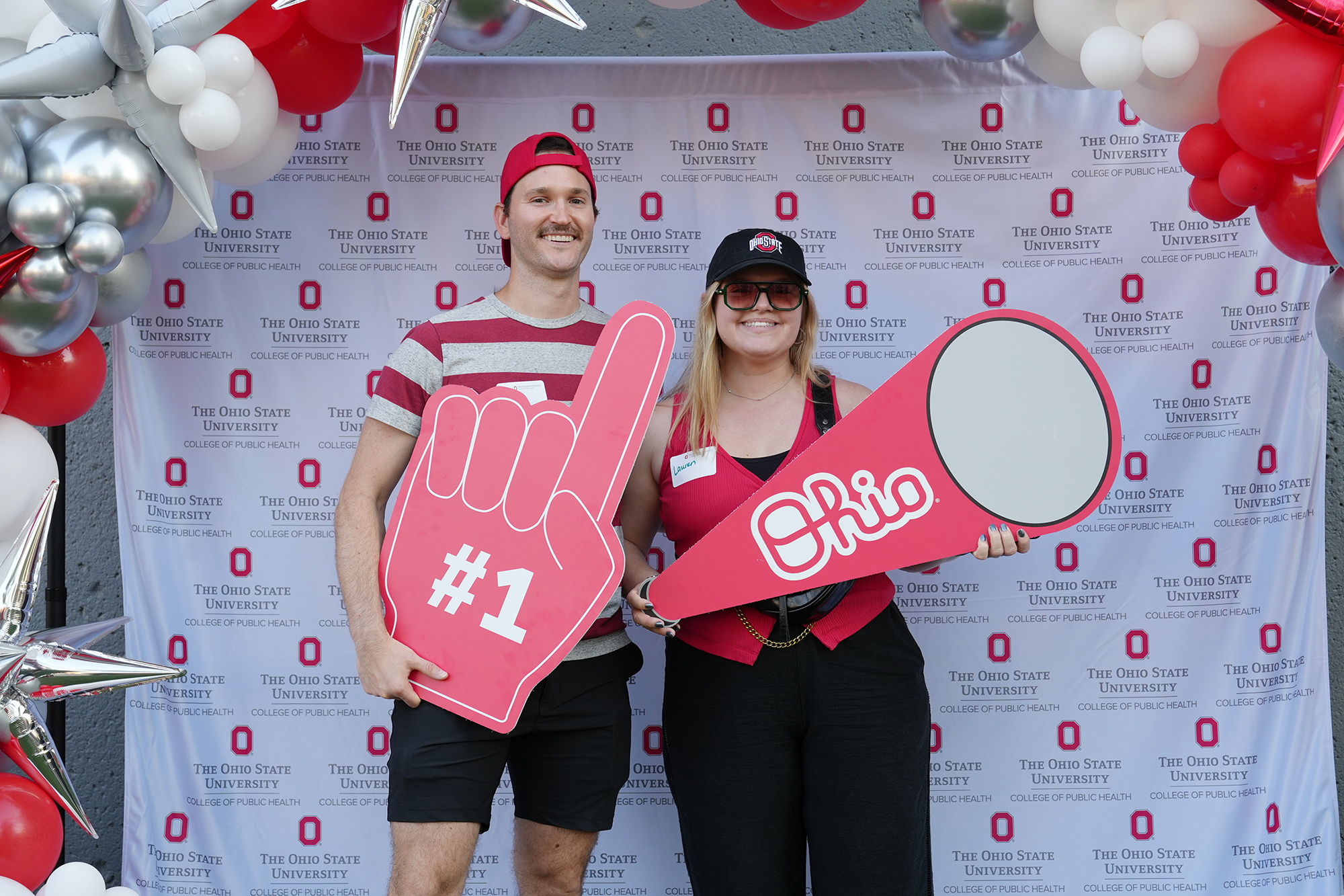 Two people in Ohio State gear pose with large props