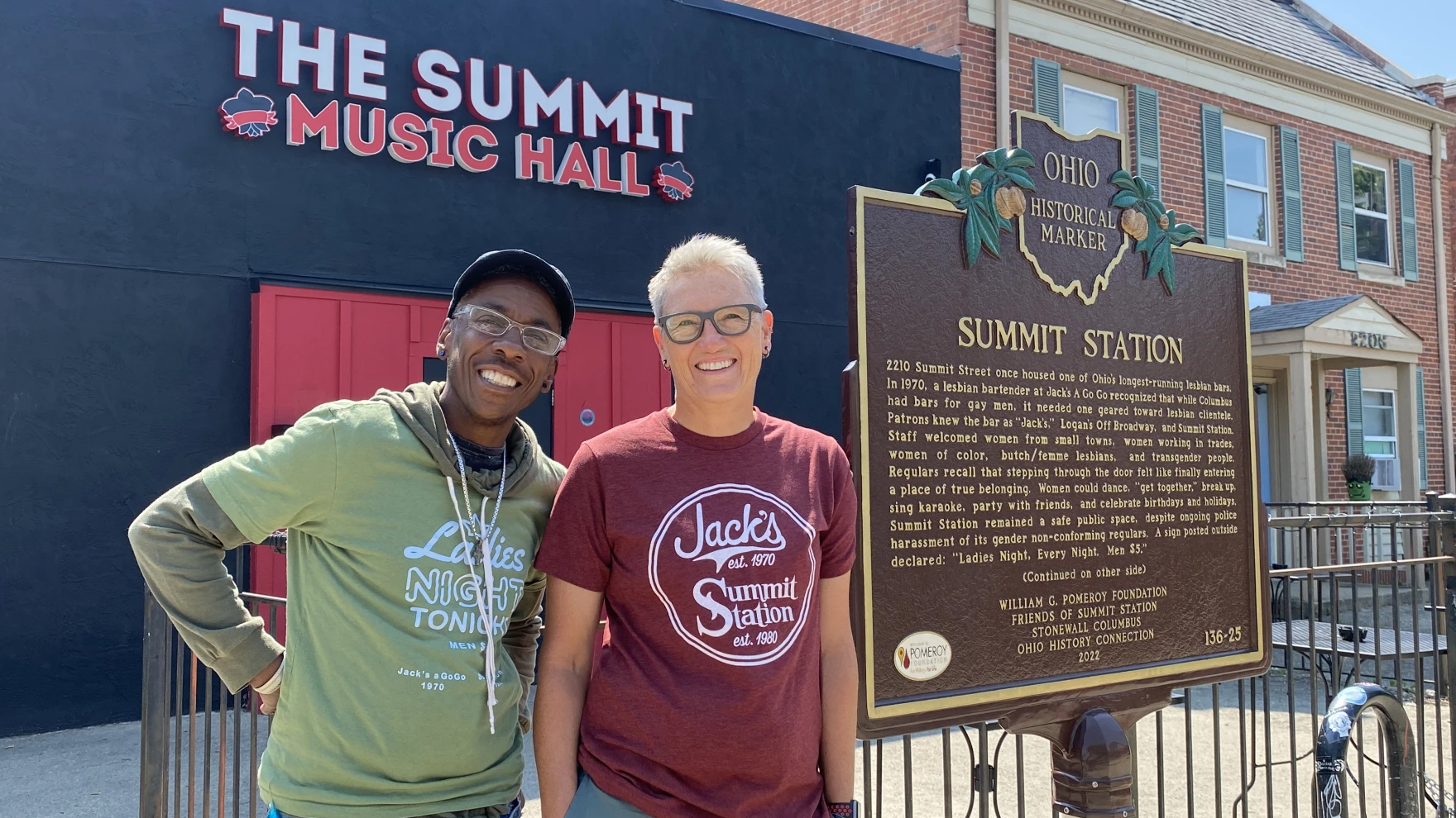 Two people stand near a brown historical marker with The Summit Music Hall in the background.