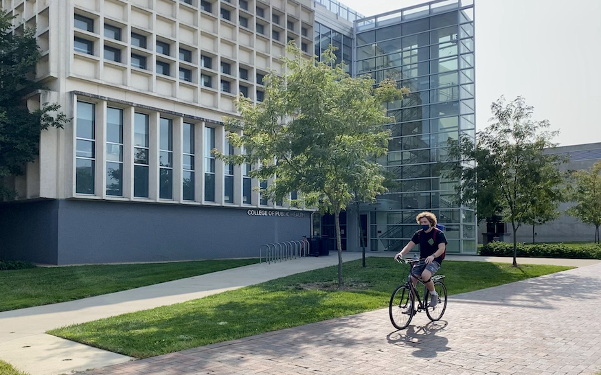 student riding bike in front of Cunz Hall