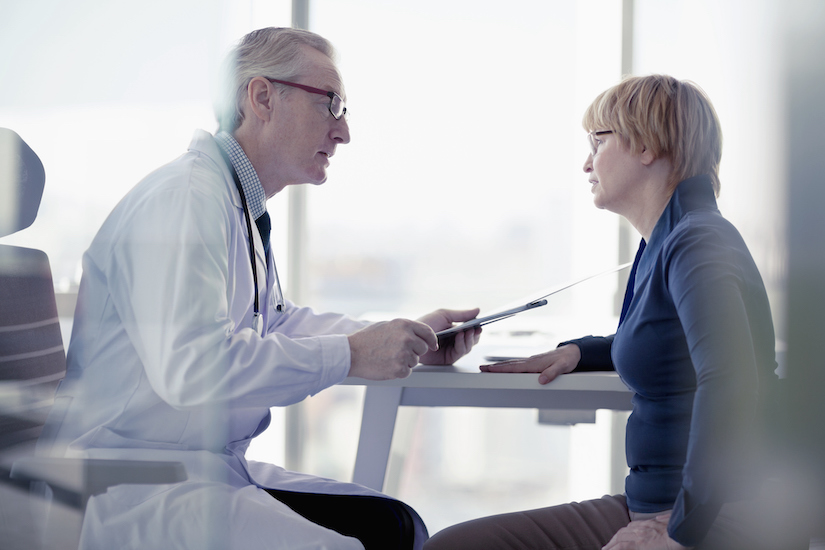 A male doctor talks to a female patient in a consultation room