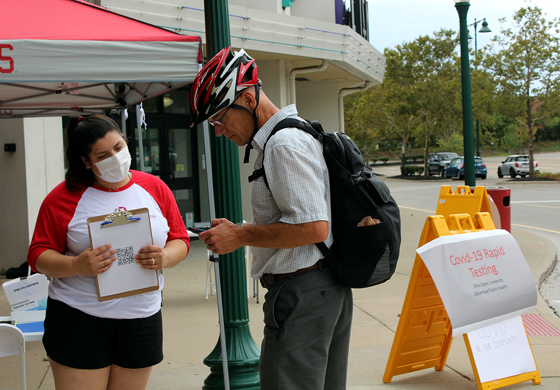 Fourth-year public health student Lauren Putz helps check in a community member for a COVID-19 test