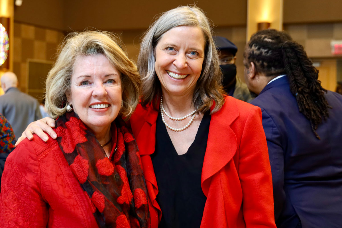 Two smiling women in bright red suit jackets