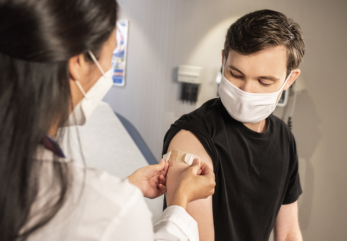 Health care worker places an adhesive bandage on a man's arm.
