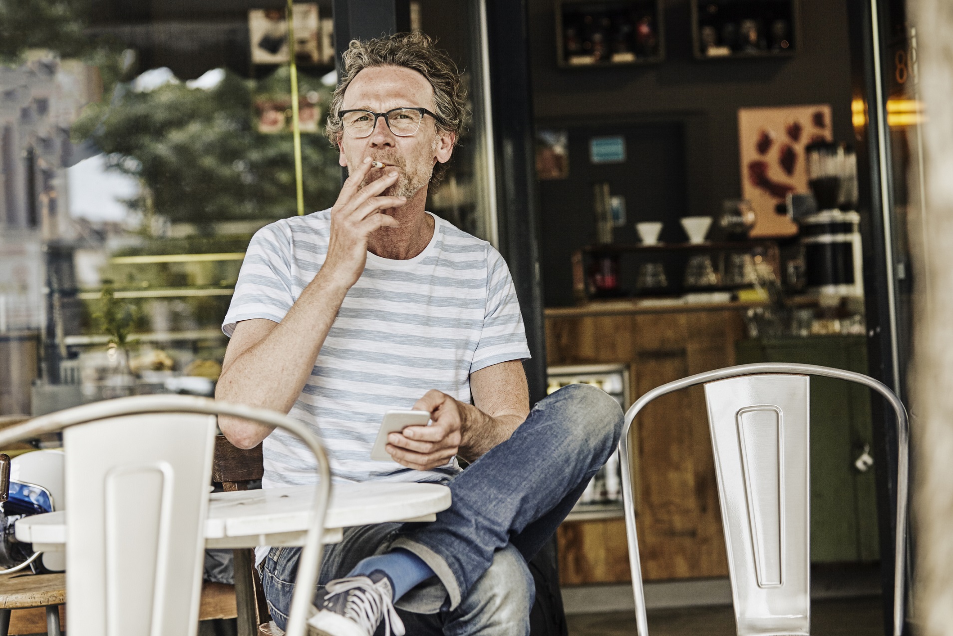 Middle-aged man smoking at an outdoor cafe