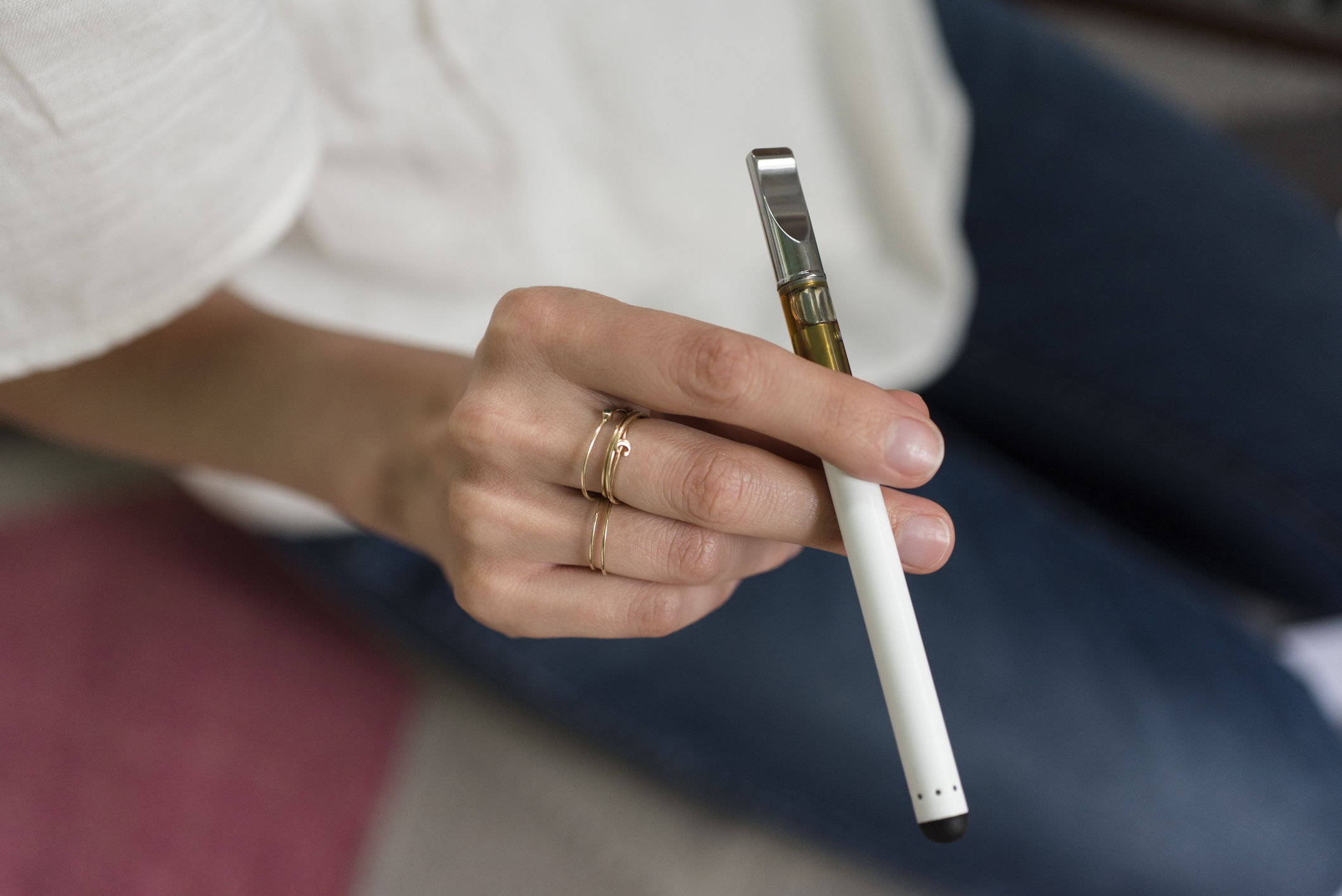 A young woman's hand, holding a vaping device