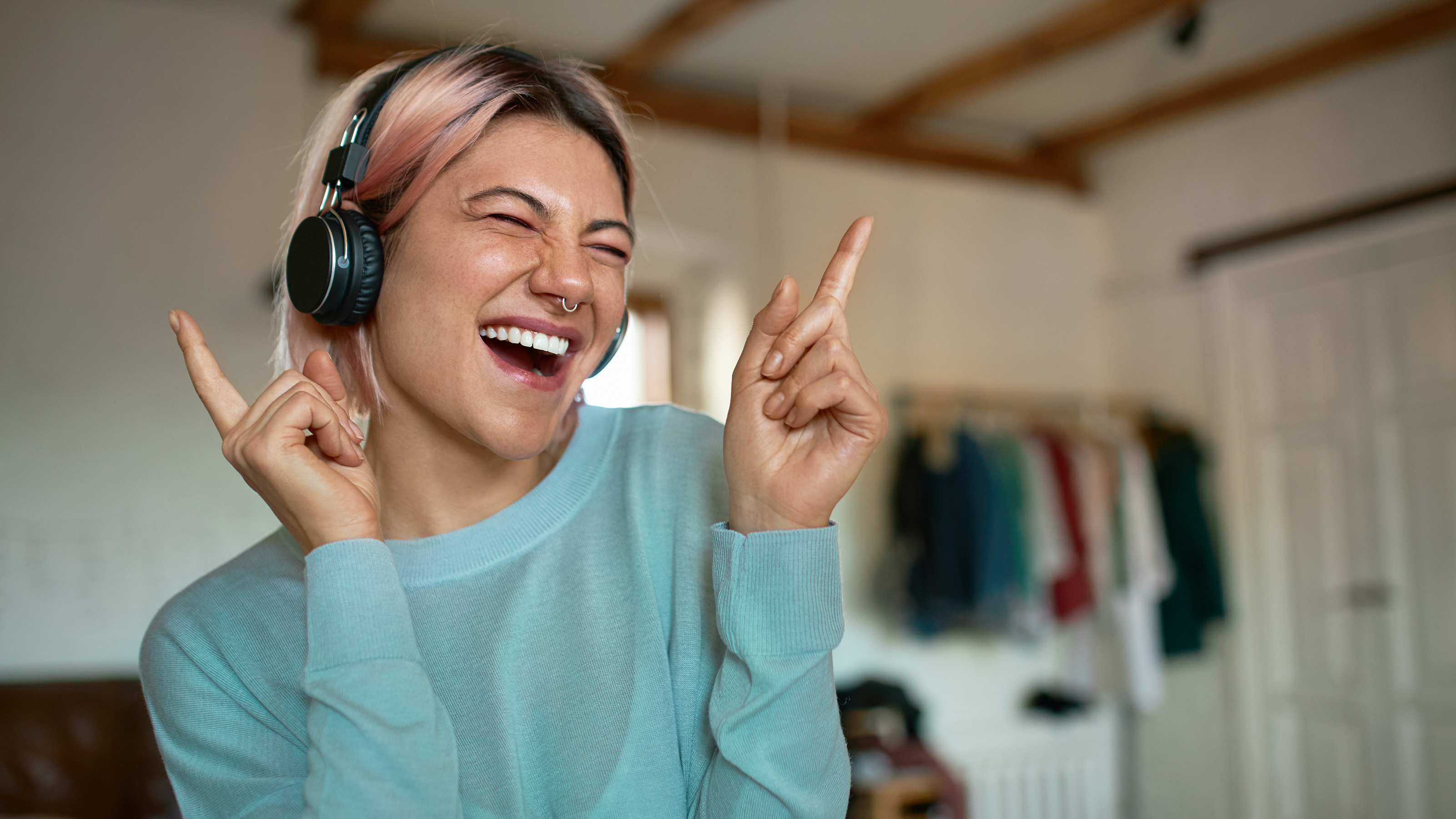 Person in a blue sweater listening to music through black headphones.