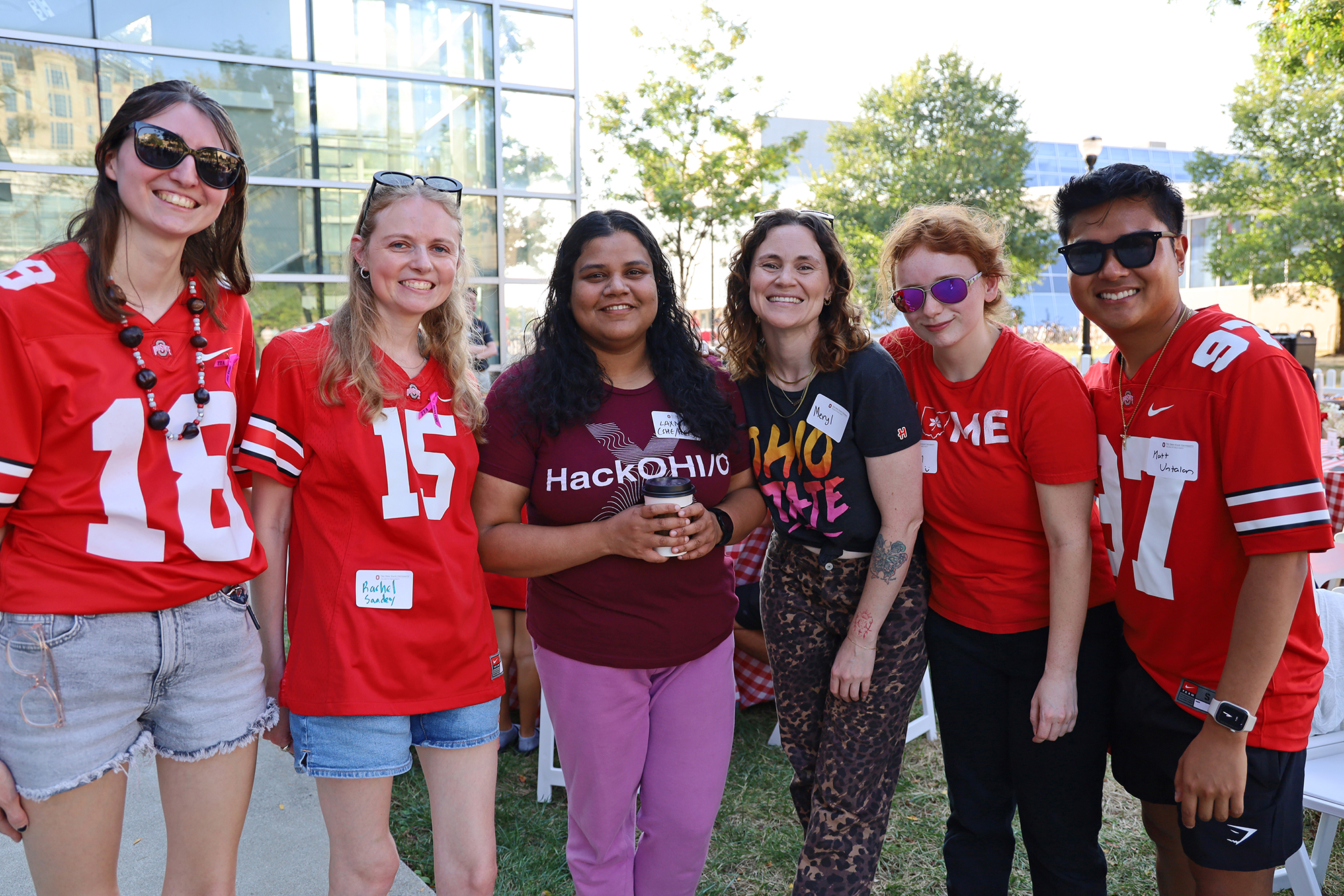 A group of students wearing Buckeye attire stand in a row.