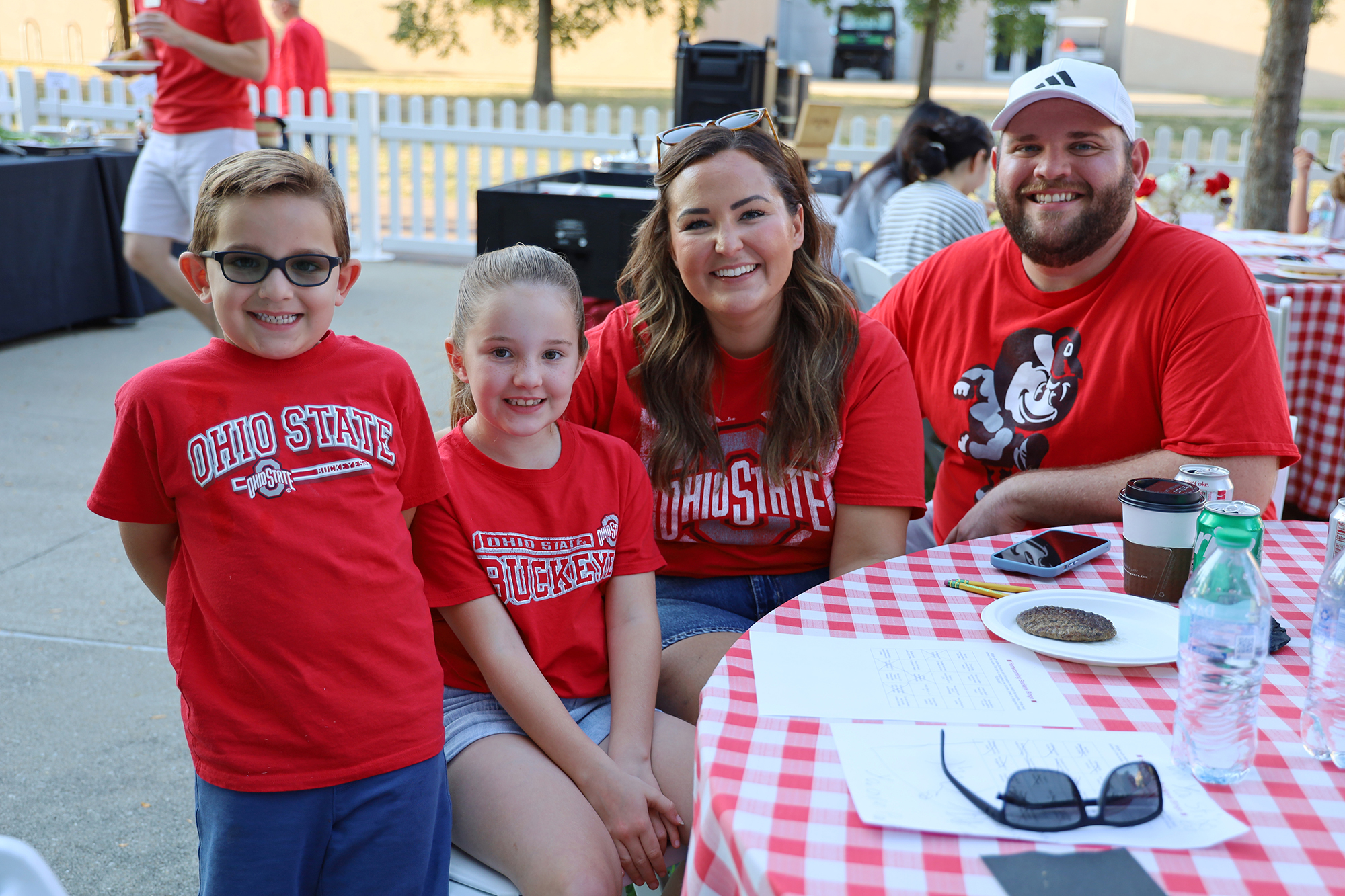two chlidren and two adults smile. They are wearing Buckeye attire.