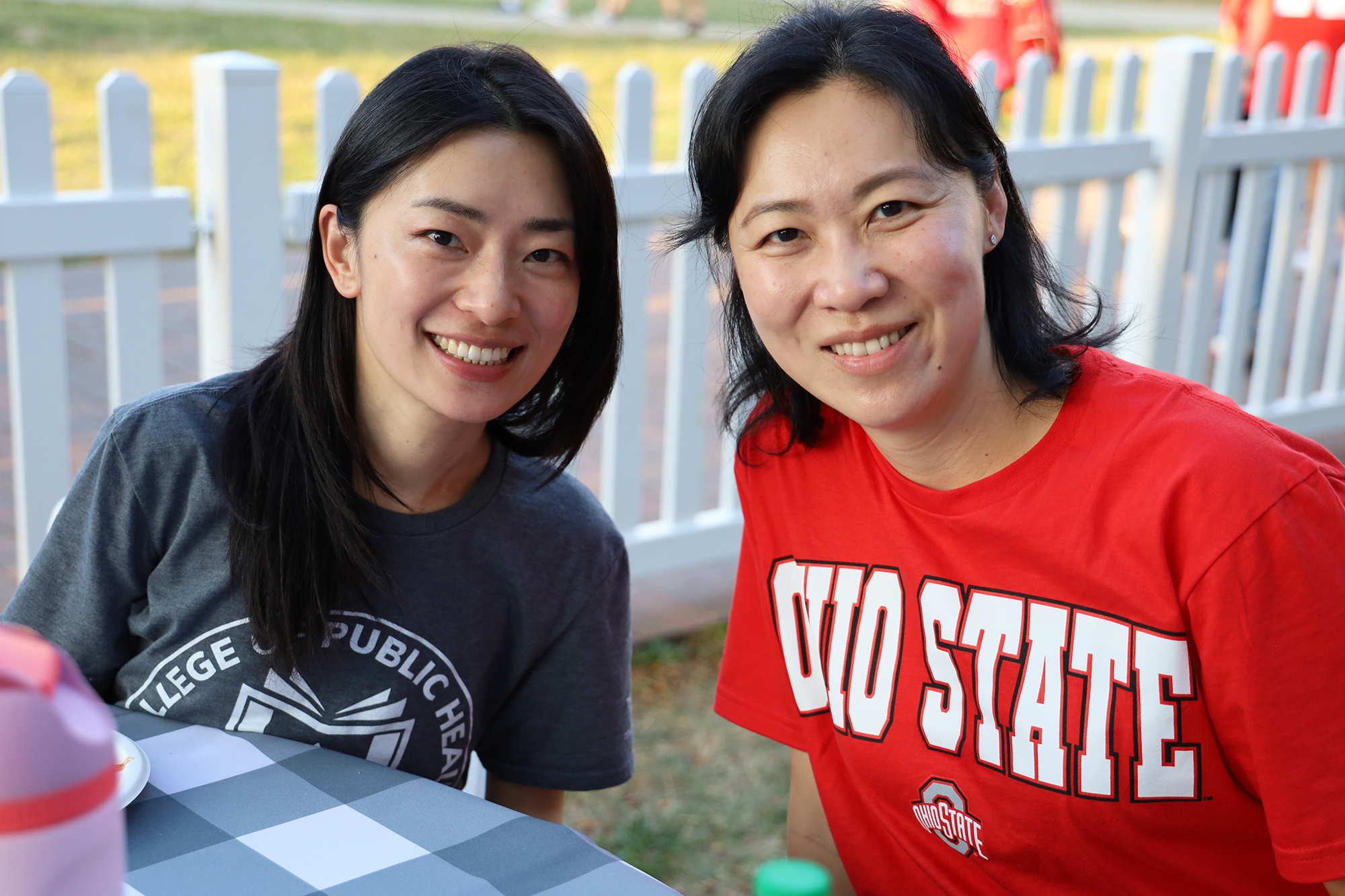 Two people smile wearing College of Public Health and Buckeye attire.