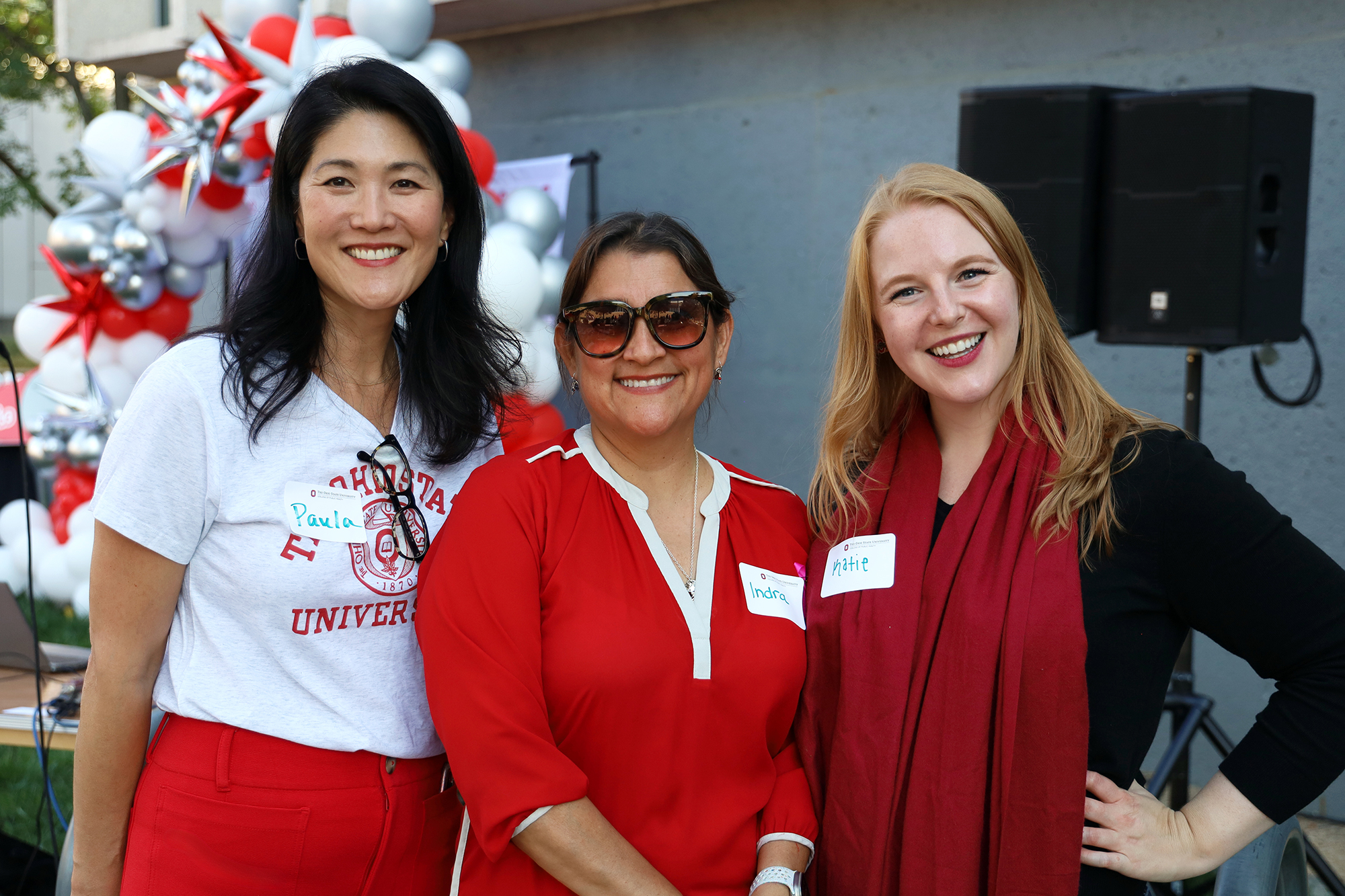 Three people smile outside