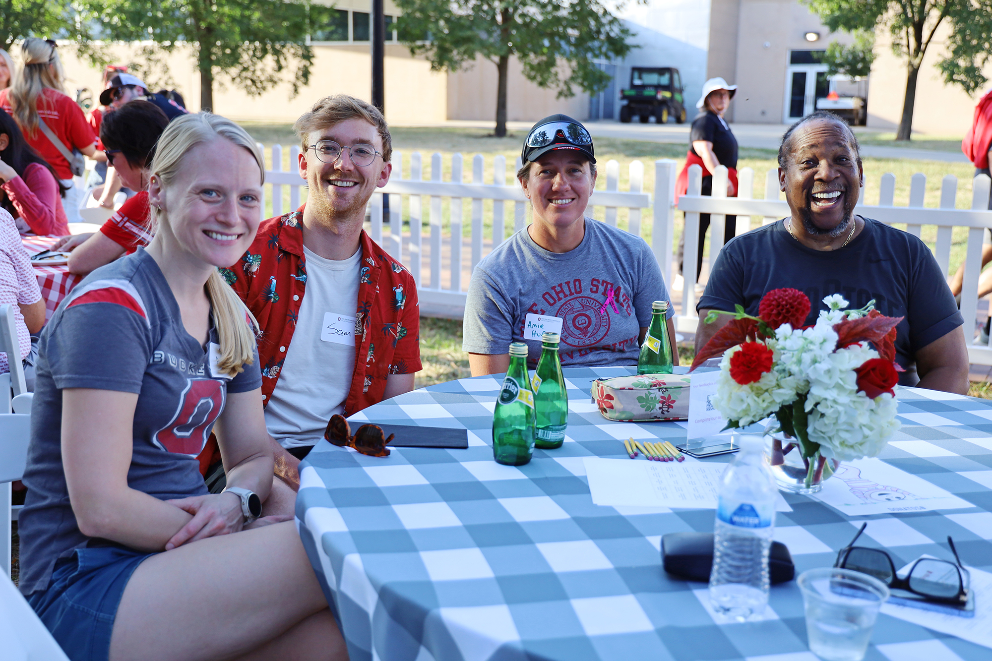 four people sit around a table outside.