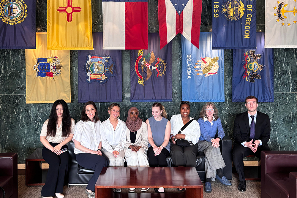 Students pose for a photo with many different flags in the background