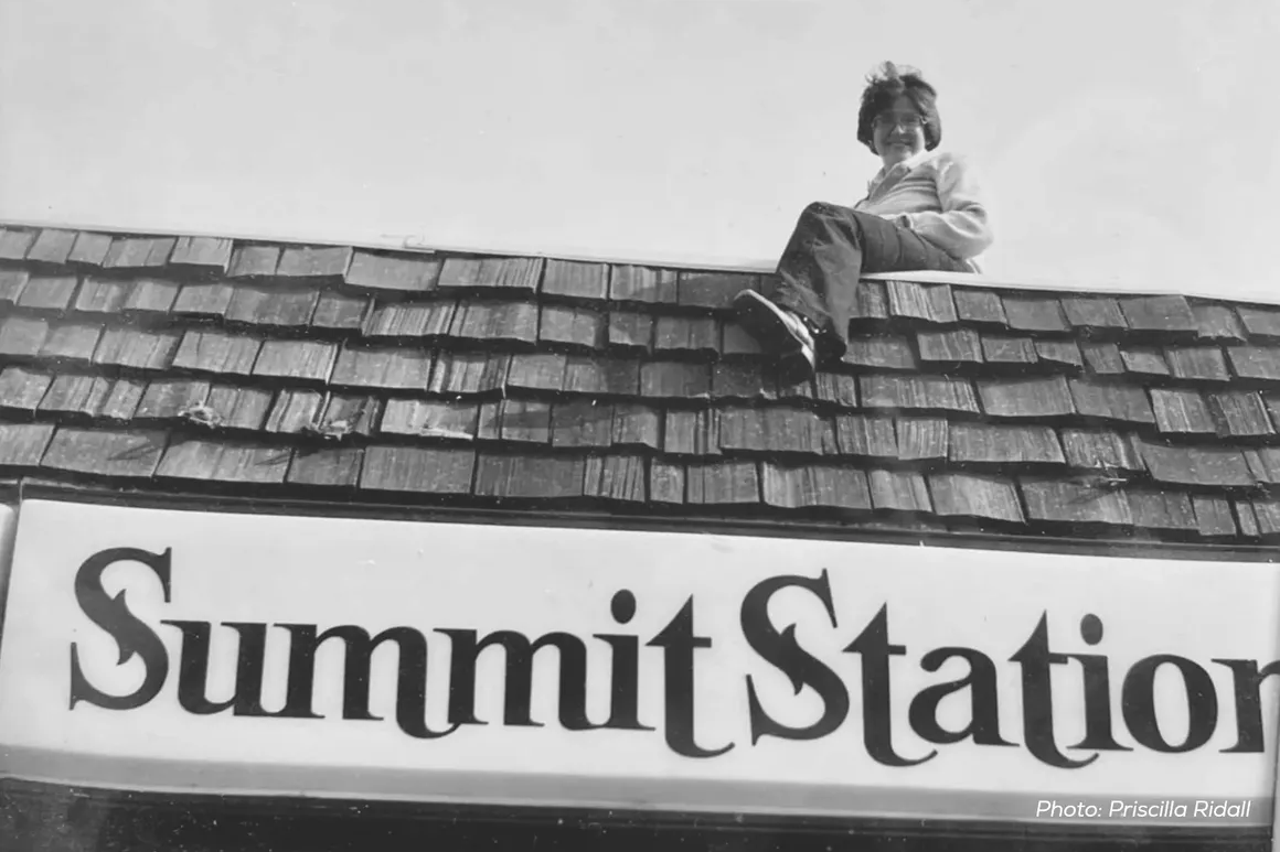 A person sits on the roof of a building with the sign Summit Station.