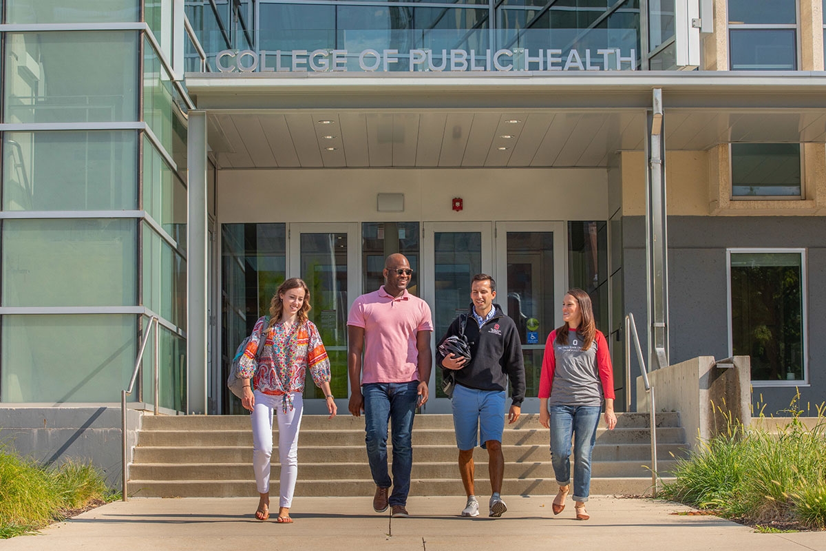 four people walking in front of Cunz Hall on sunny day