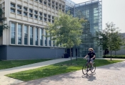 student riding bike in front of Cunz Hall