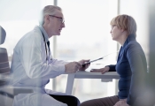 A male doctor talks to a female patient in a consultation room