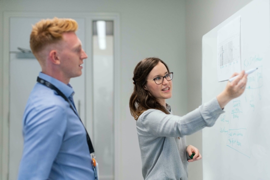 two people discussing work using white board