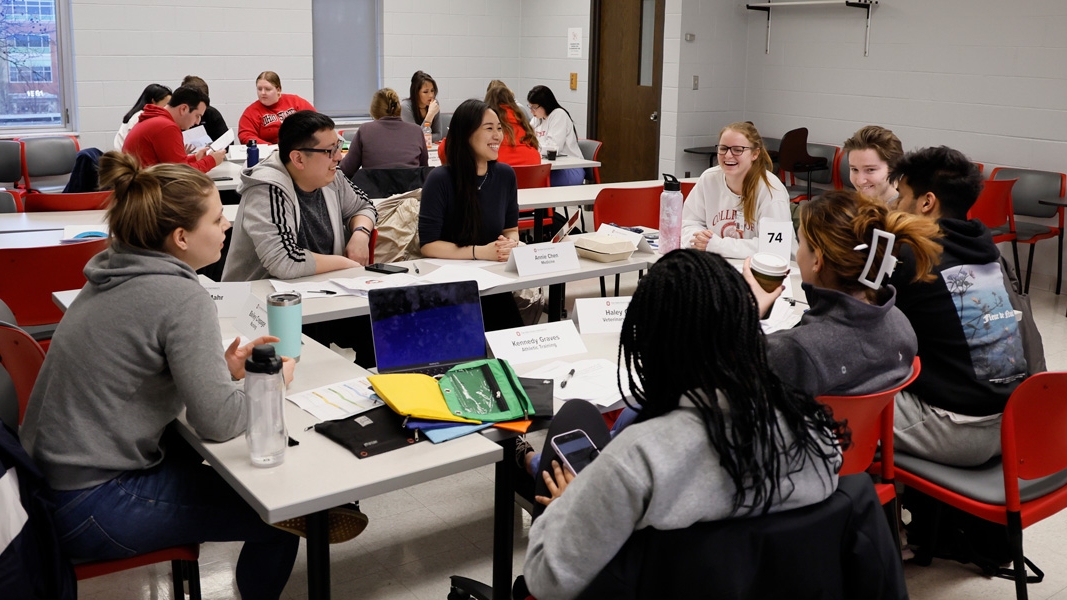 Group of Ohio State students sit around a large table talking