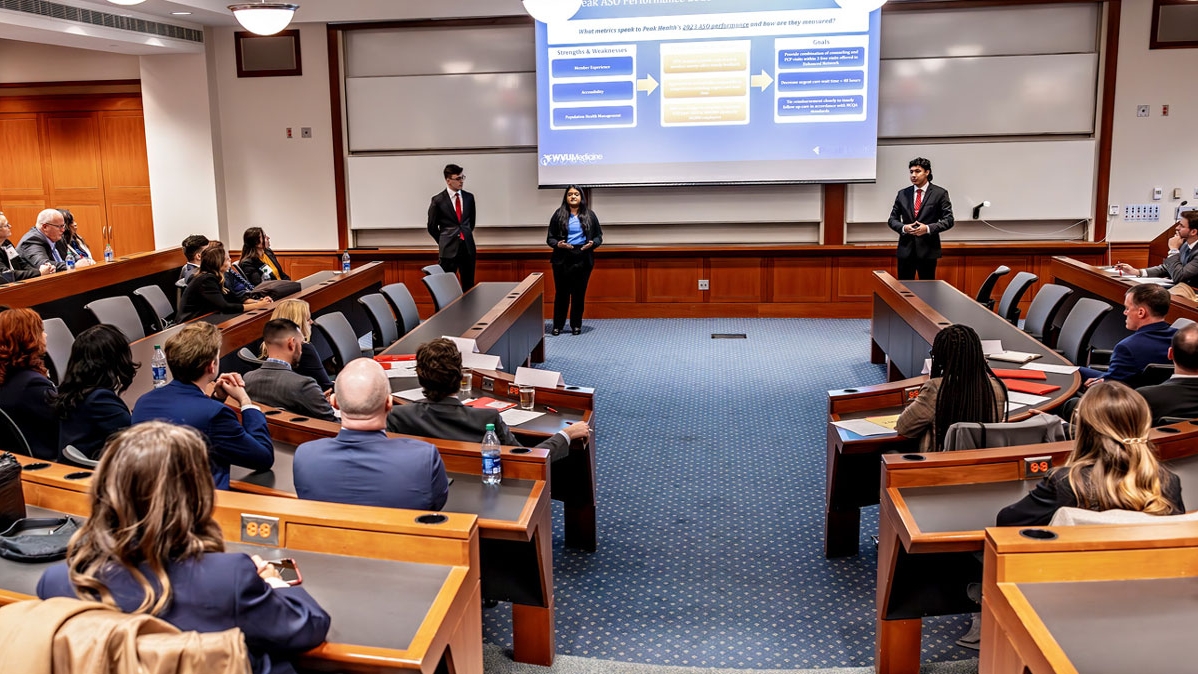 Three Master of Health Administration students practice in a conference room before the case competition.