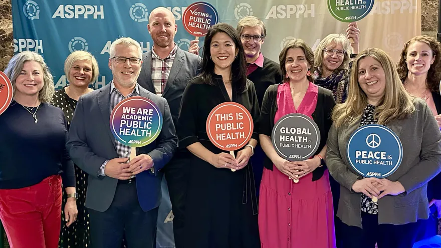 A group of people including Paula Song pose with signs supporting public health
