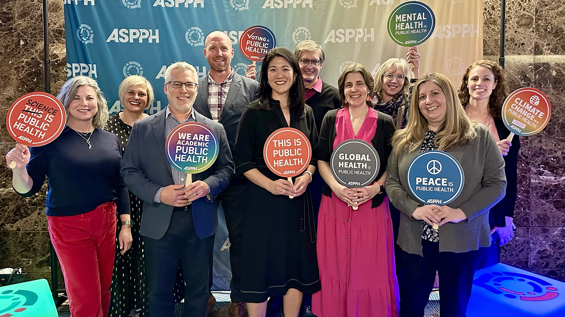 CPH faculty and staff pose with Dean Paula Song holding signs advocating for public health.
