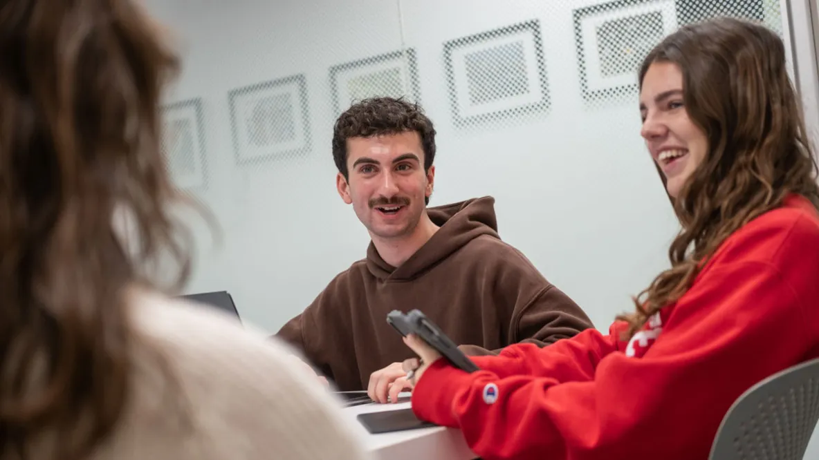 Three students in a study room discussing their course project