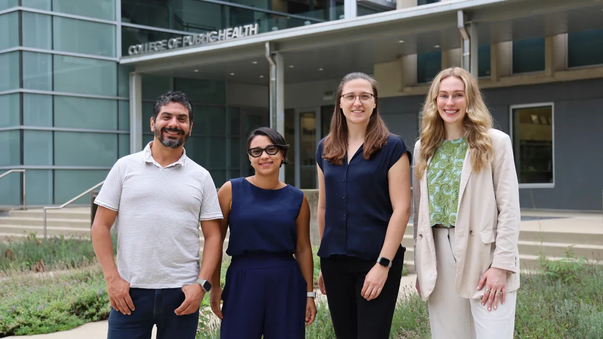 Four academics wearing business casual attire with Cunz Hall in the background.