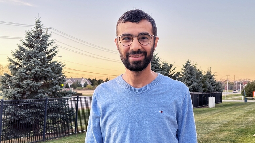 Mahmood Alalwan smiling, standing outside in front of trees