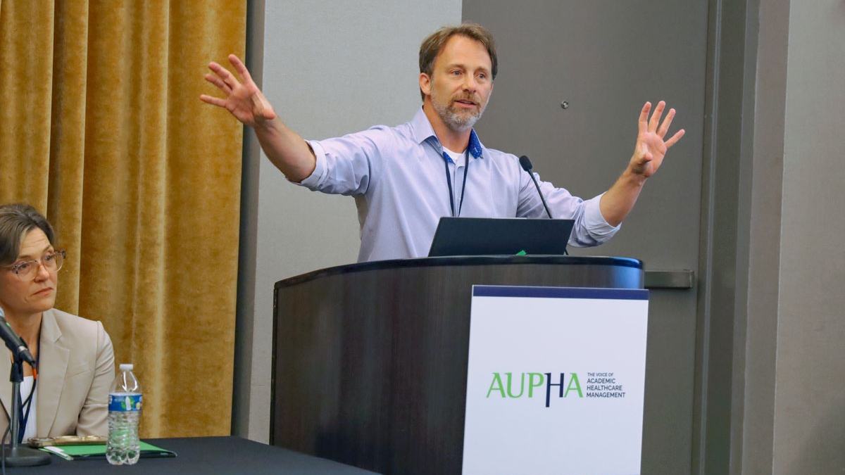 Man speaking and gesturing while standing at a podium