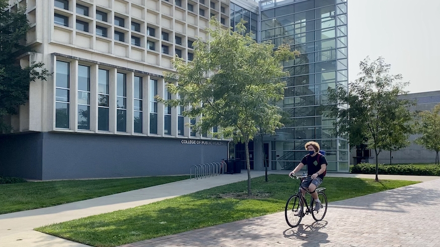 student riding bike in front of Cunz Hall