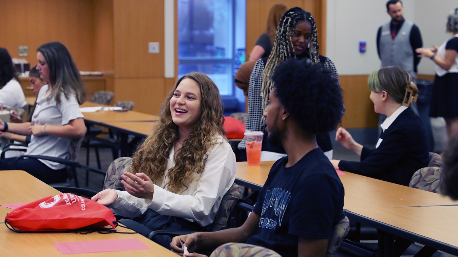 Two public health students sit at a conference room table talking