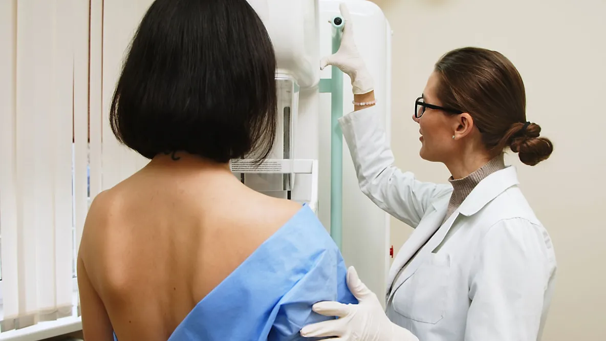 Patient gets routine breast cancer screening as doctor operates mammogram x-ray machine