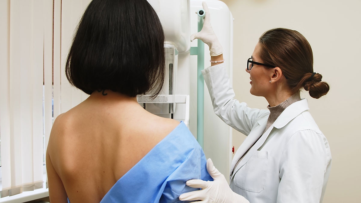 Patient gets routine breast cancer screening as doctor operates mammogram x-ray machine