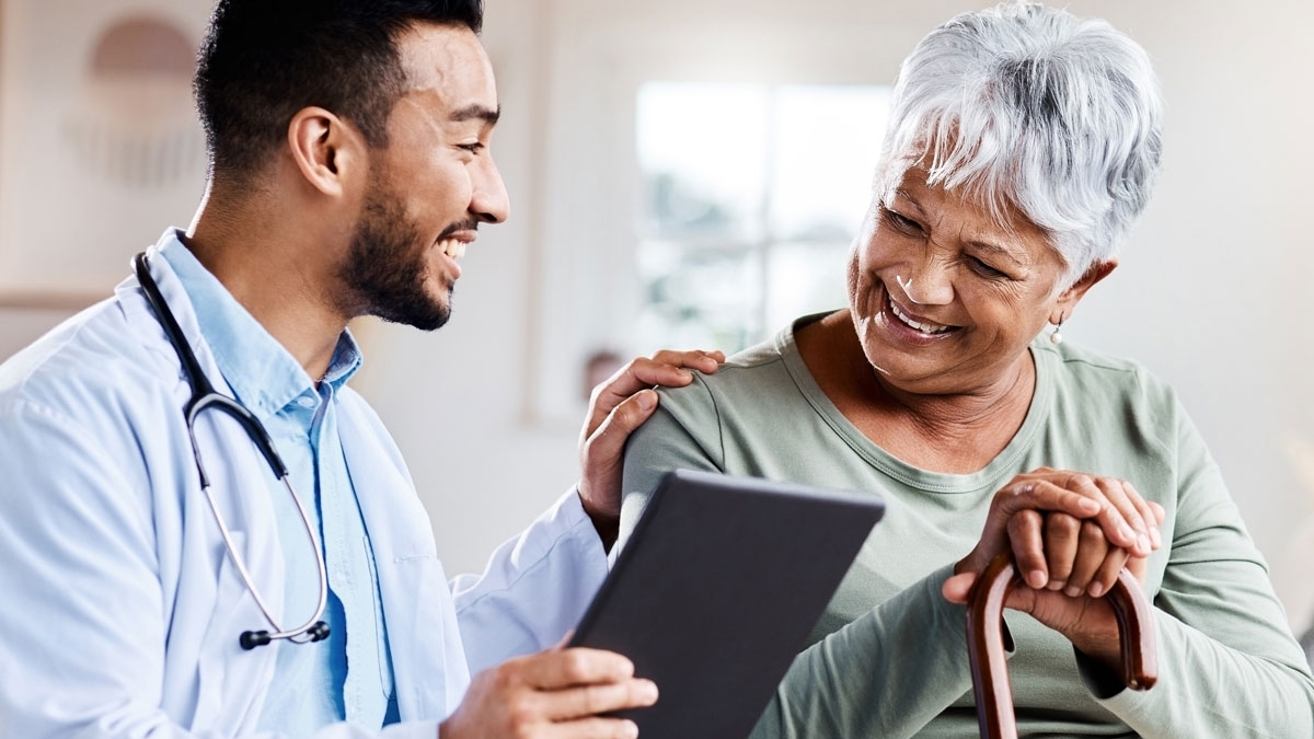 A male doctor and an elderly woman smiling together