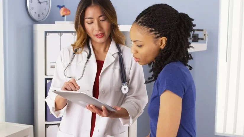 A doctor shows a woman medical information from her tablet