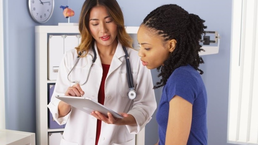 A doctor shows a woman medical information from her tablet