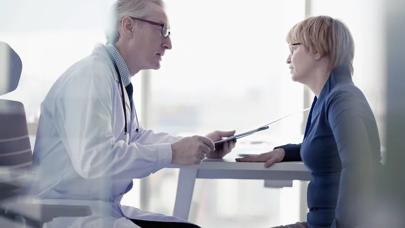 A male doctor talks to a female patient in a consultation room