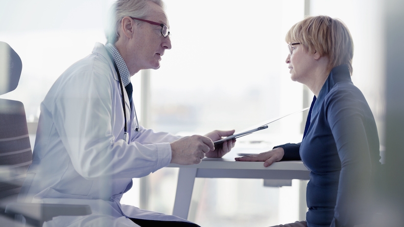 A male doctor talks to a female patient in a consultation room