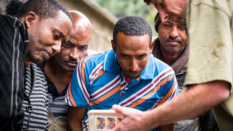 A researcher shows a water sample to members of an African community
